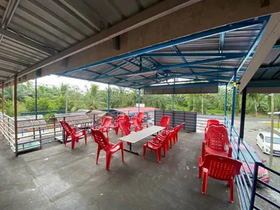 a group of red chairs and tables on a patio at Dalya's Roomstay in Tanjung Karang