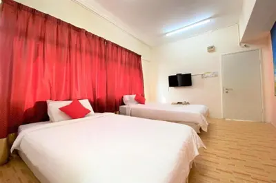 two beds in a hotel room with red curtains at B Hotel Penang in George Town