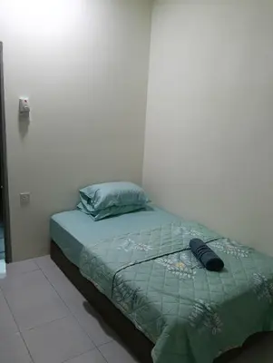 a bed with a green comforter in a room at The Welcome Mat Homestay in Seri Iskandar