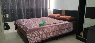 a small bed in a room with a purple bedspread at Bayu Emas Apartment in Batu Ferringhi