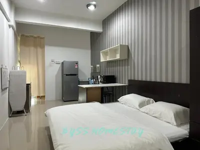 a bedroom with a bed and a kitchen with a refrigerator at BYSS Homestay Studio in Kampar
