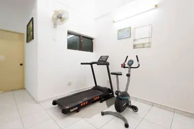 a room with a gym with a treadmill and a fan at Homie4u - Ipoh Garden East 8 pax in Ipoh