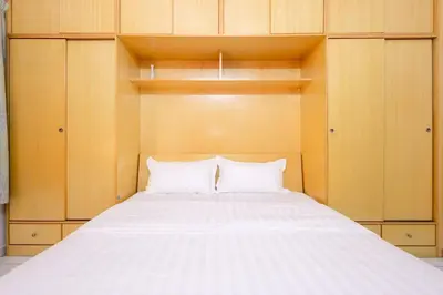 a bedroom with a large white bed with wooden cabinets at Homie4u - Ipoh Garden East 8 pax in Ipoh