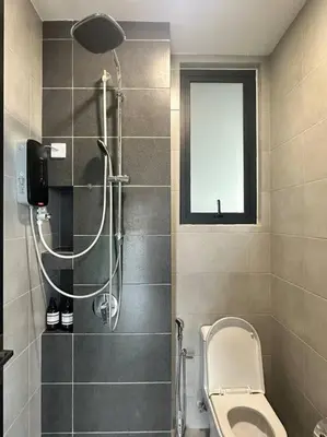 a bathroom with a shower with a toilet and a window at Urban Suites Cozy Home with Netflix and Board games in Jelutong