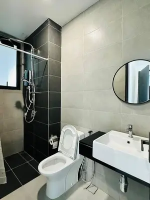 a bathroom with a toilet and a sink and a mirror at Urban Suites Cozy Home with Netflix and Board games in Jelutong