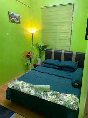 a green bedroom with a bed and a lamp at Brite Homestay Nibong Tebal in Kampong Telok