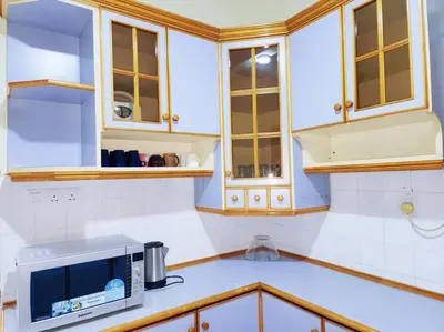 a kitchen with white cabinets and a microwave at Pengkalan 42 Double-Storey Homestay in Kampong Pinji