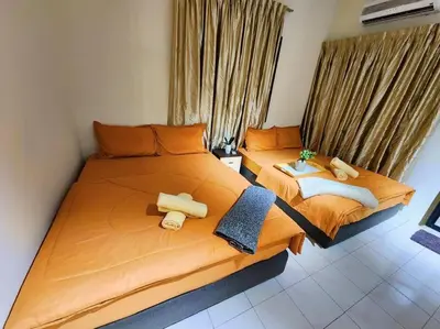 a bedroom with two beds with orange sheets at Pengkalan 42 Double-Storey Homestay in Kampong Pinji