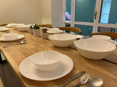 a wooden table with white bowls and plates on it at Karpal Singh Drive Seaside Georgetown 4BR-15pax by 3C in George Town