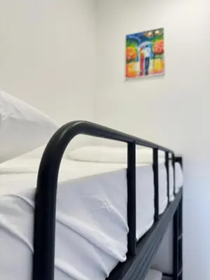 a bunk bed with white sheets and a picture on the wall at Moustachz Hauze , Georgetown in George Town