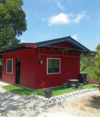 a red house with a table in front of it at Bougainvillea Garden KKB in Kuala Kubu Baharu