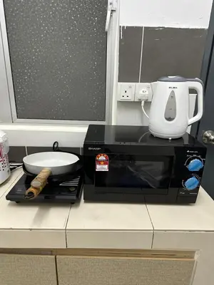 a microwave sitting on a counter with a white appliance at AYAAN HOMESTAY HiLL ViEW IIN FREE WIFI & NETFLIX in Tanah Rata