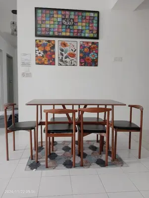 a dining room table with chairs and a painting on the wall at Nana Homestay in Parit Buntar