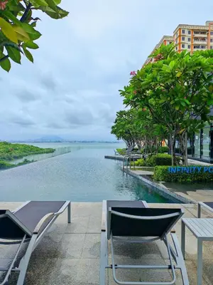 a swimming pool with chairs and a view of the water at Urban Suites - Queens Suite in Jelutong