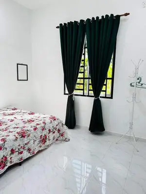 a bedroom with a bed and a window with curtains at Homestay Nurwan in Bukit Mertajam