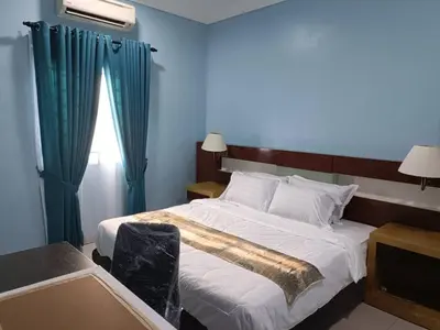 a bedroom with a large bed and a window at NHR Harmoni in Simpang Ampat