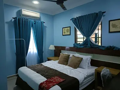 a bedroom with a bed with blue walls and a window at NHR Harmoni in Simpang Ampat