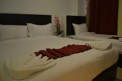two beds with white sheets and red towels on them at DR Hotel Penang in Bayan Lepas