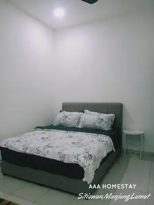 a bed in a room with a white wall at AAA homestay in Sitiawan