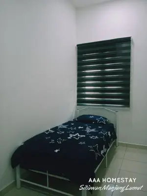 a bedroom with a bed with a blue blanket and a window at AAA homestay in Sitiawan