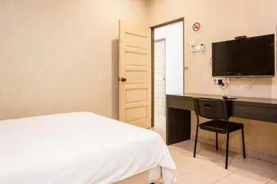 a bedroom with a bed and a desk and a television at Value Inn Homestay by uBook in Butterworth