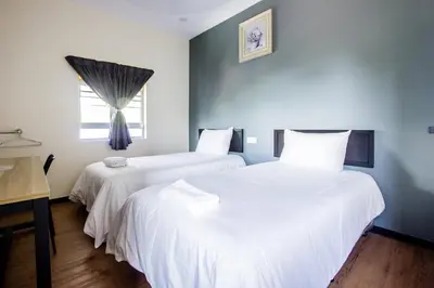 two white beds in a room with a window at Plumeria 5BR Garden House by uBook in Butterworth