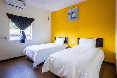 two beds in a room with a yellow wall at Plumeria 5BR Garden House by uBook in Butterworth