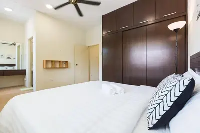 a bedroom with a large white bed with a wooden headboard at Landed 3BR Home Near Beach, Seafood & Fisherman Village in Bayan Lepas