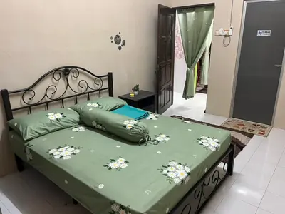 a bed with a green comforter with flowers on it at Homestay Cikgu Siti teluk intan in Teluk Intan