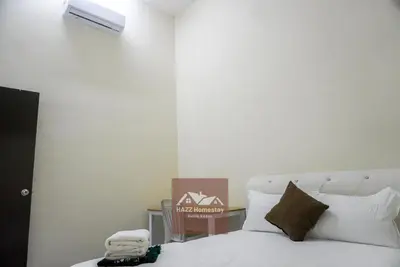 a bedroom with a bed with white sheets and pillows at HAZZ Homestay Kulim IV in Kulim