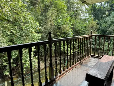a wooden balcony with a bench and trees at Villa Kuala Woh Resort in Tapah