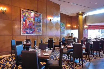 a restaurant with tables and chairs and a painting on the wall at Hotel Royal Penang in George Town