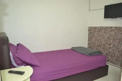 a bed with purple sheets and a remote control on it at SPOT ON 89821 Batu Maung Sempoi Inn and Cafe in Kampong Batu Maung