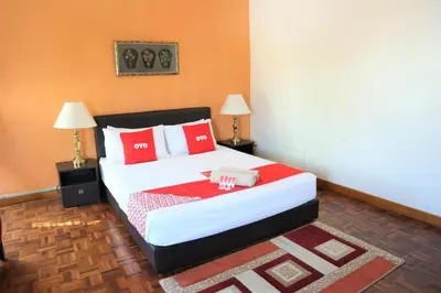 a bedroom with a large bed with red pillows at Hotel O D'hitech Home in Kampong Sungai Badak