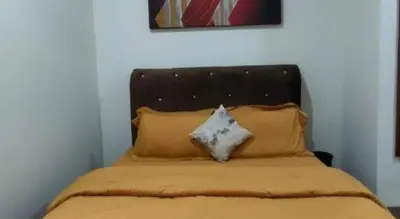 a bed with a black headboard and some pillows at OYO Home 90711 9 Roses Villa in Kampong Sahum
