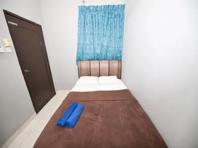 a small bedroom with a bed with a blue blanket at Hotel O Iman Roomstay Gua Musang in Kampong Keriting