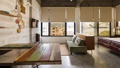 a living room with a table and a couch and windows at Belakang Kong Heng Ipoh Hotel in Ipoh