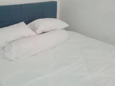 a bed with white sheets and pillows at Apartment Cameron Jaya in Tanah Rata
