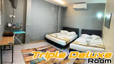 a hotel room with two beds and a table at LE dEON HOTEL Former Pine Hotel in Batu Gajah