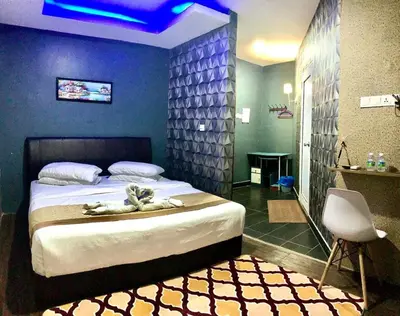 a bedroom with a large bed and a chair at LE dEON HOTEL Former Pine Hotel in Batu Gajah
