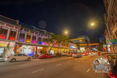 a busy city street at night with cars parked at Parlor Hotel in Ipoh