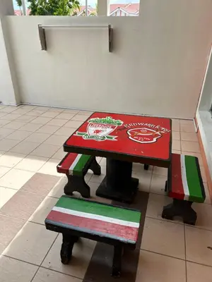 a red table with a bench in a room at AMRI KLATE Homestay in Seri Iskandar