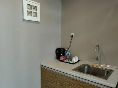 a kitchen counter with a sink and a picture on the wall at The CEO Executive Suites in Bayan Lepas