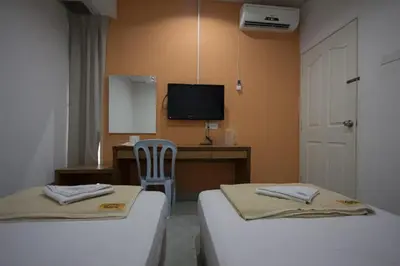 a room with two beds and a desk and a television at Bahagia Stay Georgetown in George Town