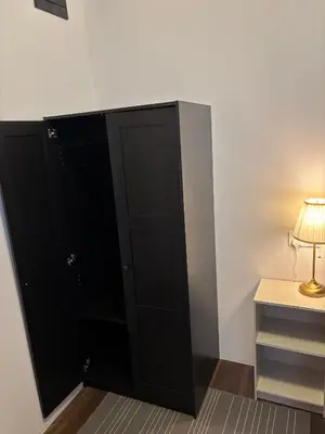 a black cabinet next to a table with a lamp at Victoria Pods in George Town