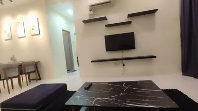 a living room with a couch and a tv on the wall at Sweet Home Ipoh Oasis Condominium in Ipoh