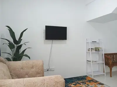 a living room with a couch and a tv on a wall at Kak Chik Homestay Tasek Gelugor in Kampong Ayer Melintas Besar