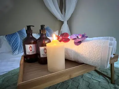 a candle and bottles on a wooden tray on a bed at Stylish&Affordable Serenity Suite #2min KekLokSi in Ayer Itam