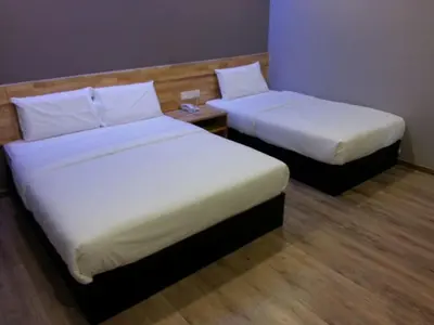 two beds in a hotel room with white sheets at JQ Suria 18 Hotel in Ipoh