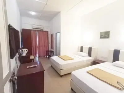 a hotel room with two beds and a desk at Collection O Analisa Beach Resort in Pangkor